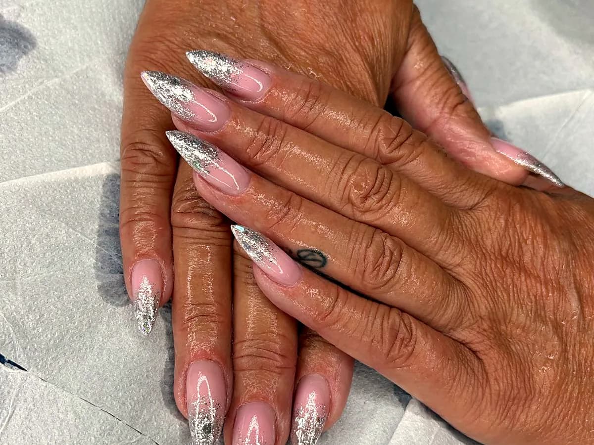 Dettaglio di nail art glitter argento su unghie a stiletto
